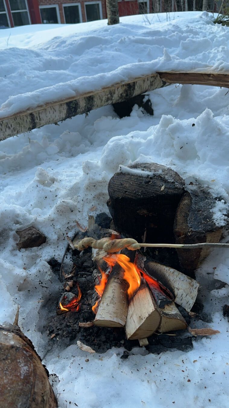 Bildet av et bål i snøen hvor det grilles pinnebrød