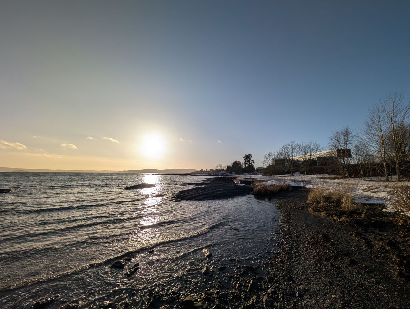Sjø, sol, strand og blå himmel